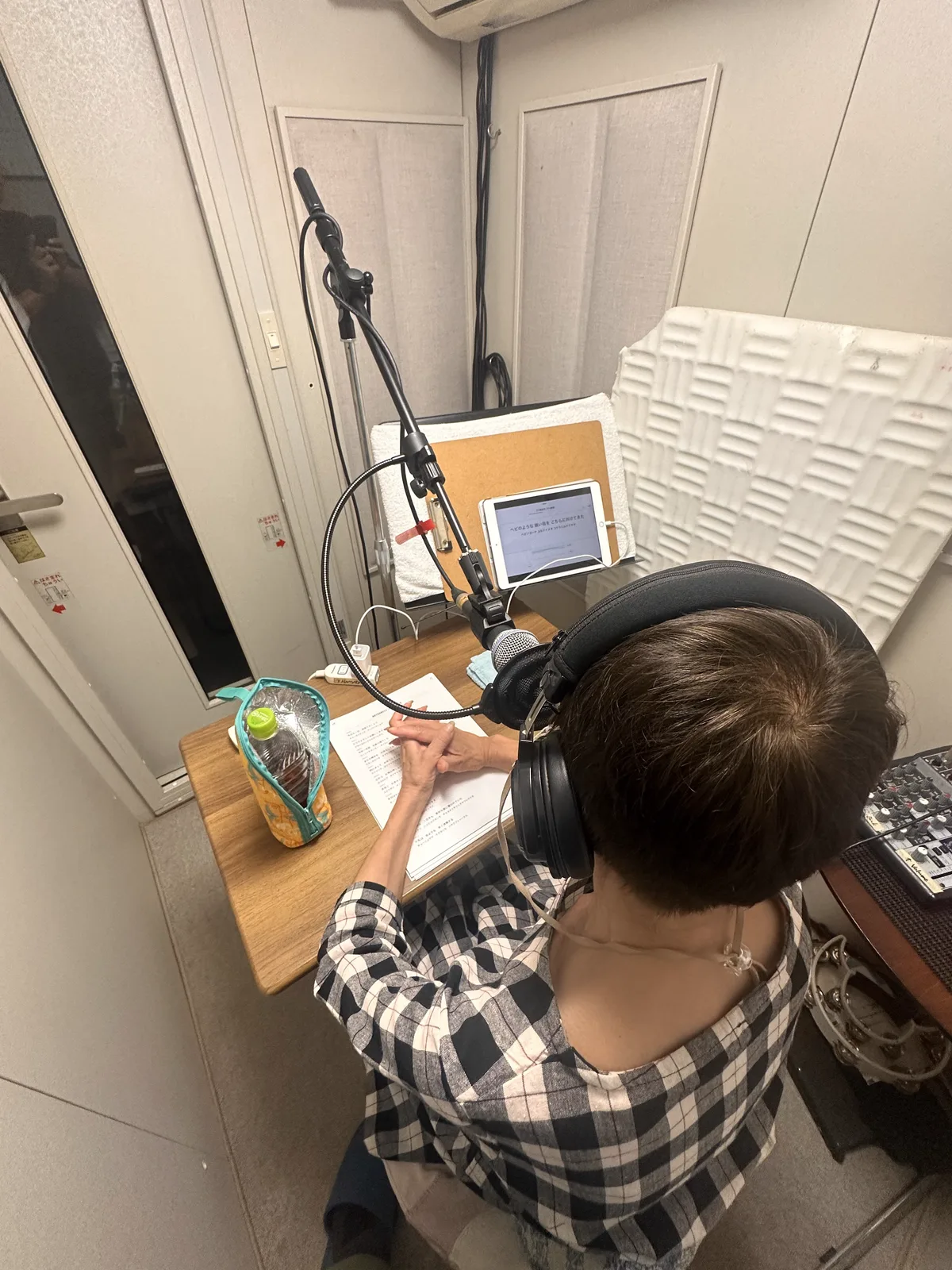 収録ブースで台本を読み上げる様子（後ろ姿）